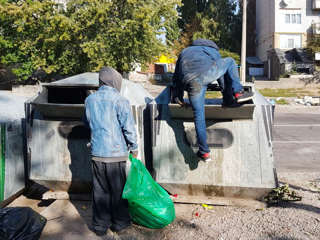 Kaksi koditonta miestä etsii ruokaa roskalavalta
